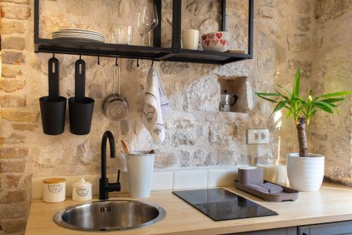 uma cozinha com um lavatório e uma parede de pedra em Rooms and Apartments Djanovic em Split