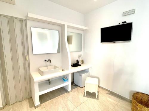 baño con lavabo y TV en la pared en La Villa Rooms en Mykonos ciudad