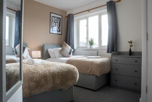 een slaapkamer met 2 bedden en een spiegel bij Comfortable 4 Bedroom Home in Milton Keynes by HP Accommodation with Free Parking, WiFi & Sky TV in Milton Keynes