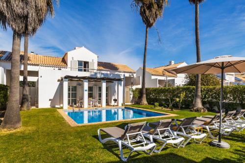 a villa with a swimming pool with chairs and an umbrella at Villa Luz do Atlantico by OCvillas in Galé
