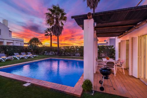 a swimming pool in a backyard with a sunset at Villa Luz do Atlantico by OCvillas in Galé