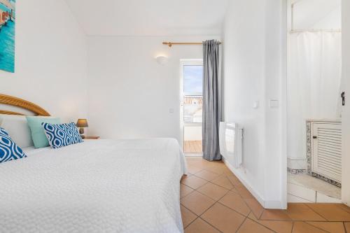 a white bedroom with a bed and a window at Villa Luz do Atlantico by OCvillas in Galé