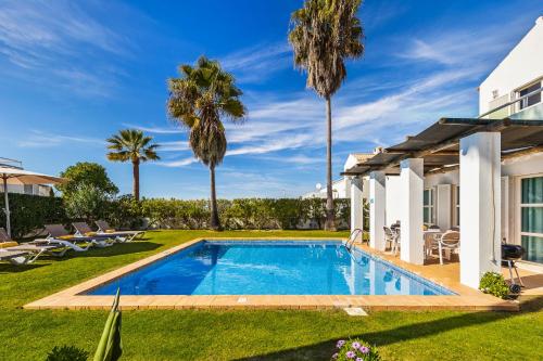 a swimming pool in a yard with palm trees at Villa Luz do Atlantico by OCvillas in Galé