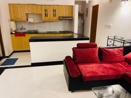 a living room with a red couch and a kitchen at Riviera palms 1 Luxury 1 BHK apartment with Swimmimg Pool view- Arpora - near baga beach in Old Goa