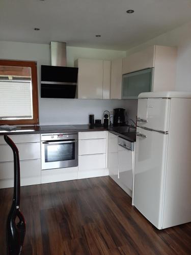 a kitchen with white cabinets and a white refrigerator at Apartment mit Terrasse und Garten in Saalfelden am Steinernen Meer