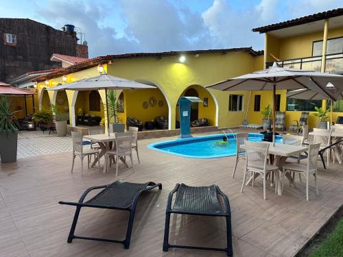 un patio con mesas y sillas y una piscina en Pousada Gamela do Maragogi, en Maragogi