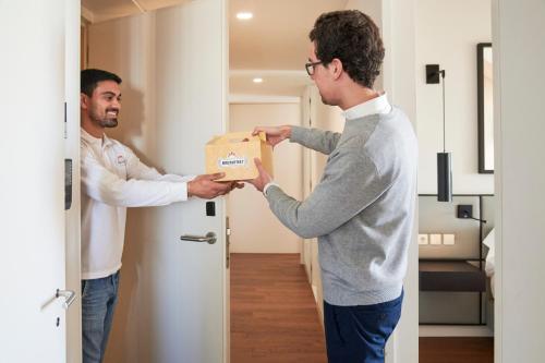 Zwei Männer stehen in einem Raum und halten eine Kiste. in der Unterkunft Lisbon Five Stars Apartments Combro 7 in Lissabon