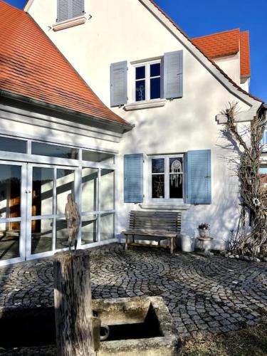 un edificio blanco con un banco delante en Sonnige Wohnung mit Garten am fränkischen Seenland en Kammerstein