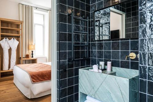 a bathroom with a black tiled wall at Hôtel Le Mosaïque in Narbonne