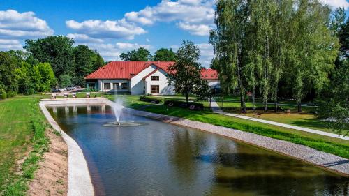 a house with a fountain in the middle of a river at Hotel Prezydent in Spała