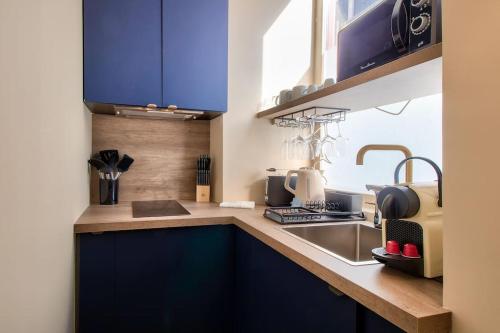 - une cuisine avec des placards bleus, un évier et un comptoir dans l'établissement Cozy apartement historic Center Paris & Montmartre, à Paris