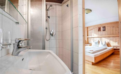 a bathroom with a sink and a shower with a bed at Wiesenhof in Kaunerberg