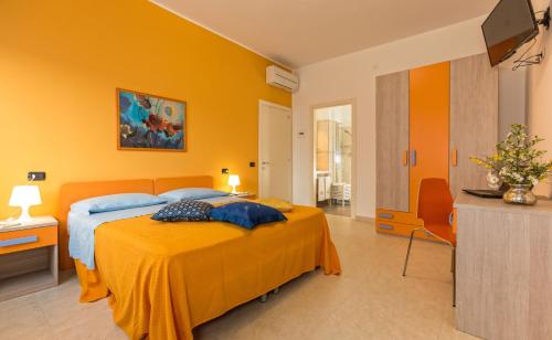 una camera gialla con letto e televisore di B&B Mazzini ad Alba Adriatica