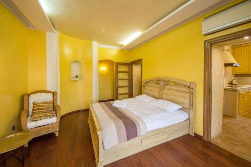 a yellow bedroom with a bed and a chair at DayFlat Apartments Maidan Area in Kyiv
