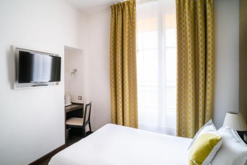a hotel room with a bed and a window and a desk at Hôtel Le Colisée in Paris
