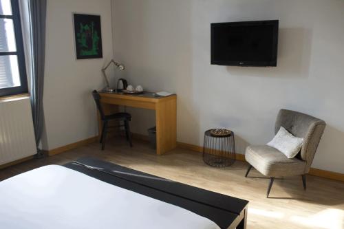 a bedroom with a bed and a desk and a television at Hôtel Absolu in Castelsarrasin