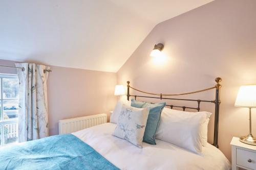 a bedroom with a bed with blue and white pillows at Host & Stay - Honey Cottage in Hinderwell