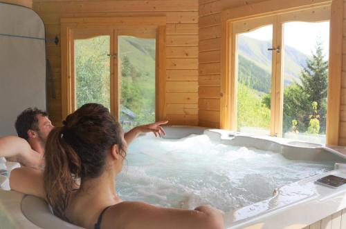 un homme et une femme dans une baignoire dans l'établissement Le Domaine du Trappeur, à Saint-Sorlin-dʼArves