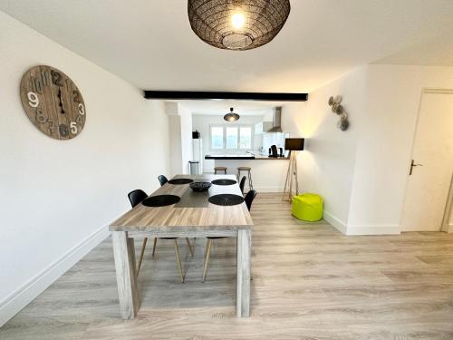 comedor con mesa y reloj en la pared en Appartement T3 cosy – Entre bourg et plages, en Ploemeur