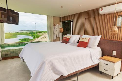 a bedroom with a large white bed and a large window at Pousada Kiriri in Itarema