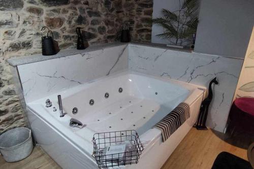 - białą wannę w pokoju z kamienną ścianą w obiekcie Precioso Apartamento 2 Hab con Bañera Hidromasaje w mieście O Barco de Valdeorras