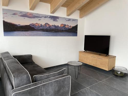 salon z kanapą i telewizorem z płaskim ekranem w obiekcie Dolomia Apartments & Spa w mieście Dimaro
