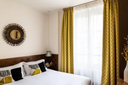 a bedroom with a bed and a mirror and a window at Hôtel Le Colisée in Paris