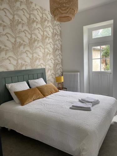 um quarto com uma cama com lençóis brancos e um papel de parede em Clos des Chardons - Le Jardin em Saint-Aignan