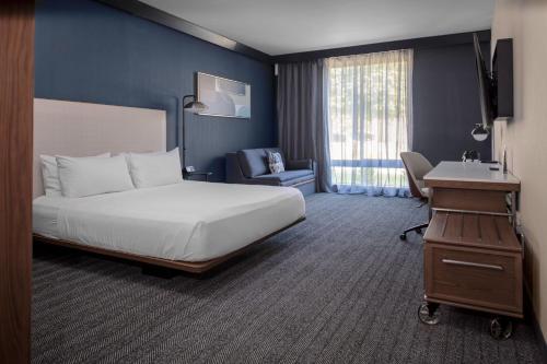 Habitación de hotel con cama, silla y escritorio. en Courtyard by Marriott Memphis East Galleria en Memphis