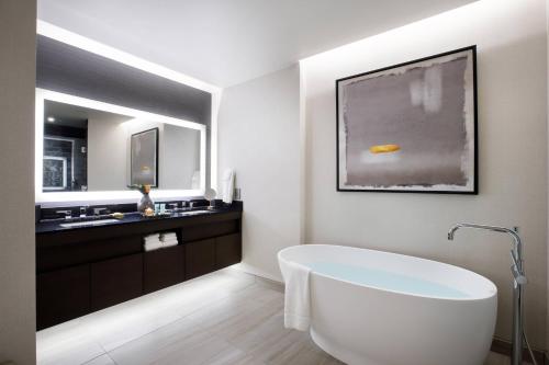 ein Badezimmer mit einer weißen Badewanne und einem Waschbecken in der Unterkunft Hotel Vin, Autograph Collection in Grapevine