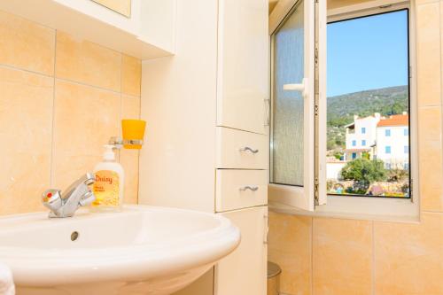 baño con lavabo y ventana en Apartment Chiara Martinscica, en Martinšćica