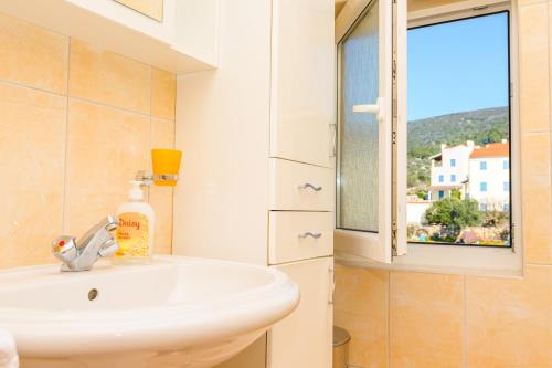 ein Bad mit einem Waschbecken und einem Fenster in der Unterkunft Apartment Chiara Martinscica in Martinšćica