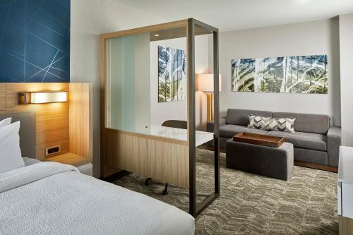 SpringHill Suites by Marriott Columbus Dublin في دبلن: غرفة نوم بسرير واريكة ومرآة