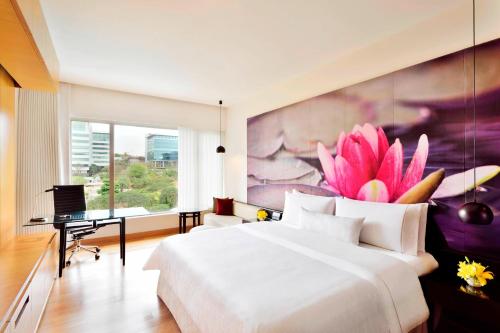 a bedroom with a large white bed and a large painting at The Westin Hyderabad Mindspace in Hyderabad