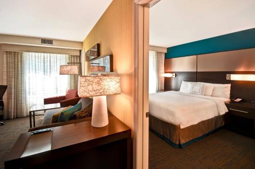 Residence Inn by Marriott Springfield Chicopee في شيكوبي: غرفة في الفندق بها سرير ومكتب به مصباح