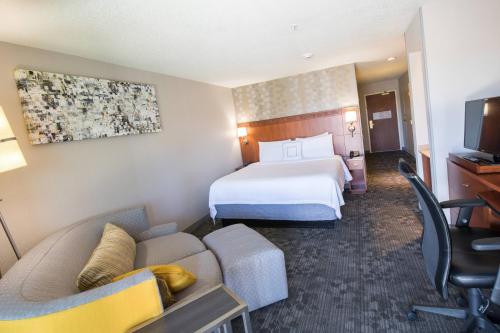 a hotel room with a bed and a couch at Courtyard by Marriott Merced in Merced