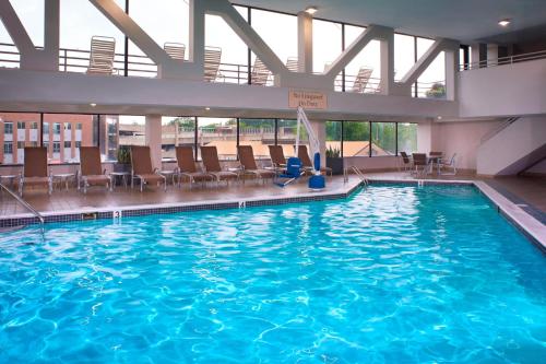 a large swimming pool in a building with chairs at Marriott East Lansing at University Place in Lansing