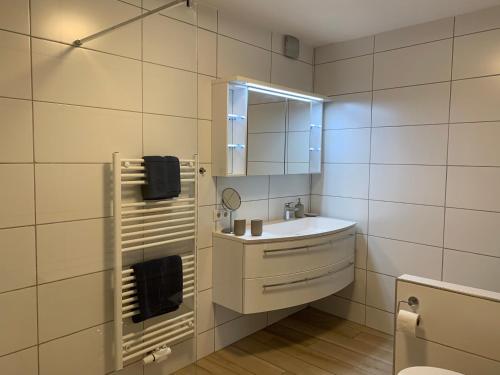 een witte badkamer met een wastafel en een spiegel bij Schusterbrand Appartements in Absam