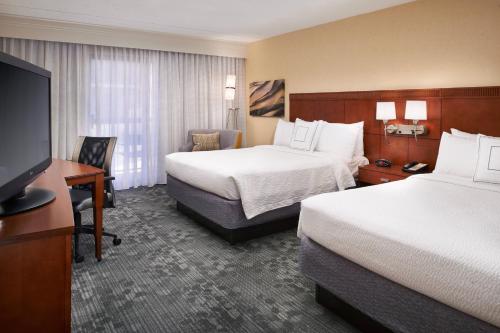 a hotel room with two beds and a flat screen tv at Courtyard Chicago Deerfield in Deerfield