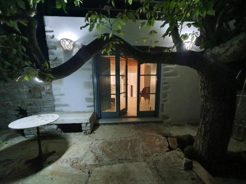 a tree with a bench in front of a door at PYRGOS - Traditional house at Kaloxilos, Naxos in Khalkíon