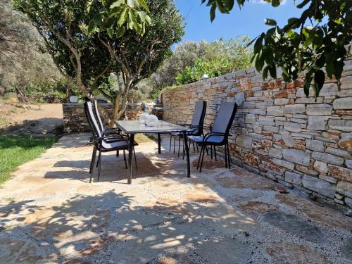 a table and chairs sitting next to a stone wall at PYRGOS - Traditional house at Kaloxilos, Naxos in Khalkíon