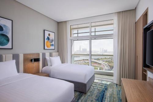 Residence Inn by Marriott Al Jaddaf في دبي: غرفة فندقية بسريرين ونافذة