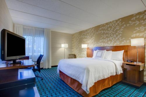 a hotel room with a bed and a flat screen tv at Fairfield Inn by Marriott Burlington Williston in Burlington