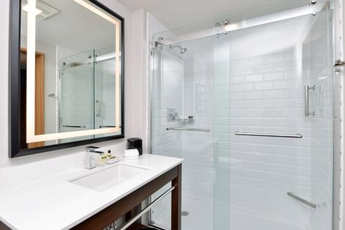 uma casa de banho com um lavatório e um chuveiro com um espelho. em Four Points by Sheraton Kansas City Olathe em Olathe