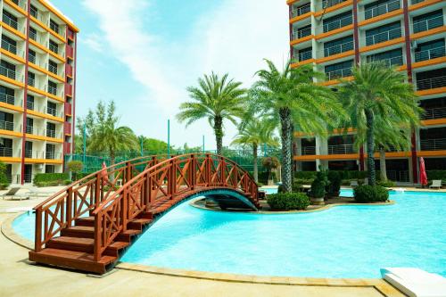 a bridge over a pool in a resort with palm trees at 777 Beach Condo Phuket in Mai Khao Beach
