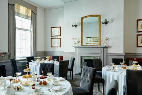 a dining room with tables and chairs and a mirror at London Marriott Hotel County Hall in London