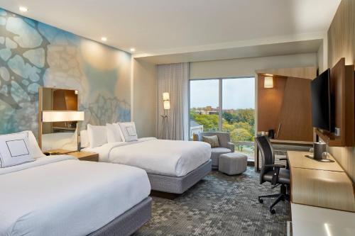 a hotel room with two beds and a desk at Courtyard by Marriott Albany Airport in Albany