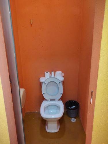 a bathroom with a toilet in an orange stall at Casa Pretahub in Cachoeira