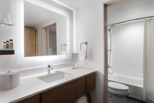 a bathroom with a sink and a toilet and a mirror at Delta Hotels by Marriott™ Virginia Beach Waterfront Suites in Virginia Beach