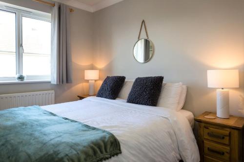 a bedroom with a bed with two lamps and a mirror at Waters Edge - stylish marina retreat in Pevensey